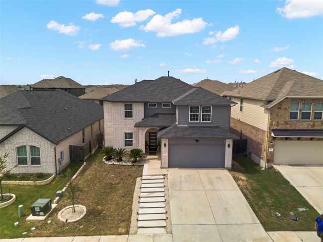 View of front of home with brick siding, driveway, an attached garage, a front yard, and roof with shingles | Image 32