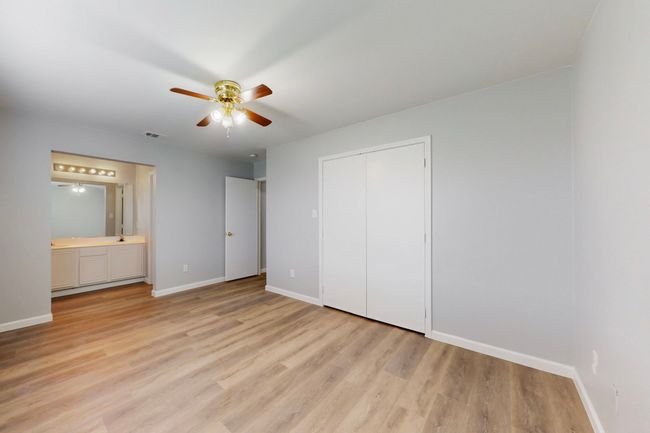 Unfurnished bedroom with connected bathroom, light wood-style flooring, a closet, baseboards, and a ceiling fan | Image 31