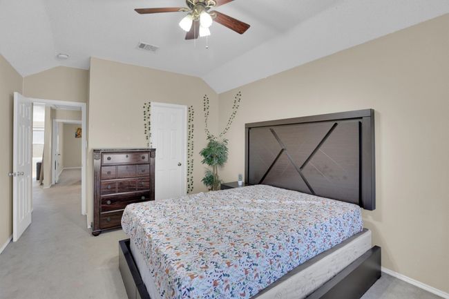 Bedroom with lofted ceiling, light colored carpet, a ceiling fan, baseboards, and visible vents | Image 33