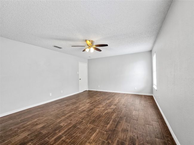 Empty room featuring ceiling fan, dark wood-style flooring, baseboards, and a textured ceiling | Image 7