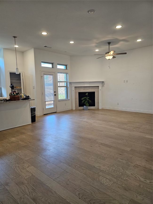Unfurnished living room with wood finished floors, ceiling fan, recessed lighting, and a fireplace | Image 8