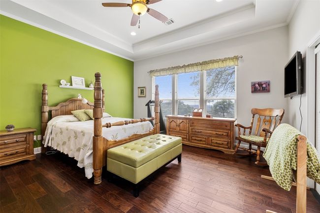 Bedroom with dark wood-style flooring, a tray ceiling, and ornamental molding | Image 10