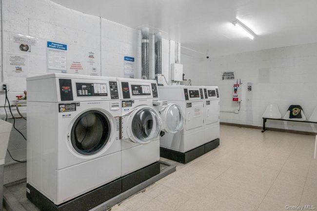 Community laundry room featuring washer and clothes dryer and concrete block wall | Image 26