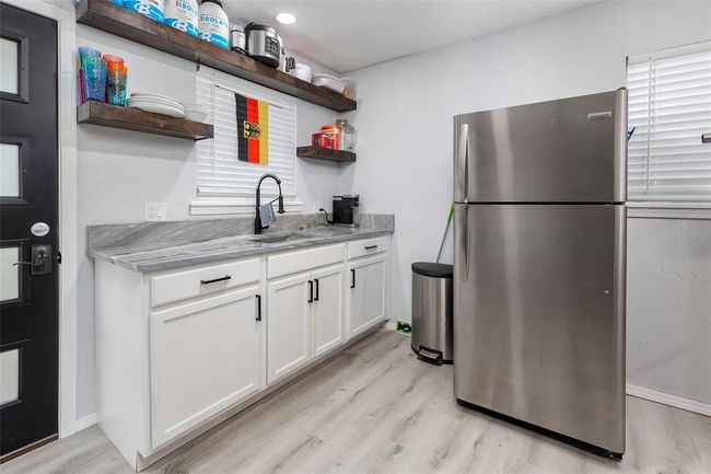 Kitchen with white cabinetry, light hardwood / wood-style floors, sink, stainless steel refrigerator, and light stone counters | Image 13