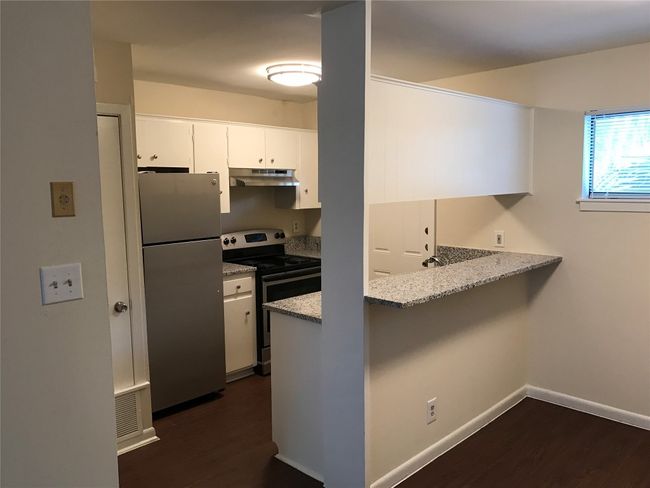 Kitchen with stainless steel range with electric stovetop, under cabinet range hood, dark wood finished floors, freestanding refrigerator, and a peninsula | Image 12