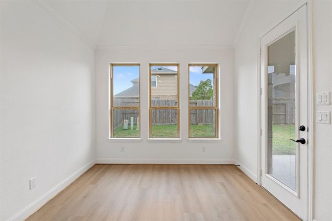 The breakfast area is filled with natural light from multiple windows, features durable vinyl flooring, and offers easy access to the backyard for seamless indoor-outdoor living. | Image 5