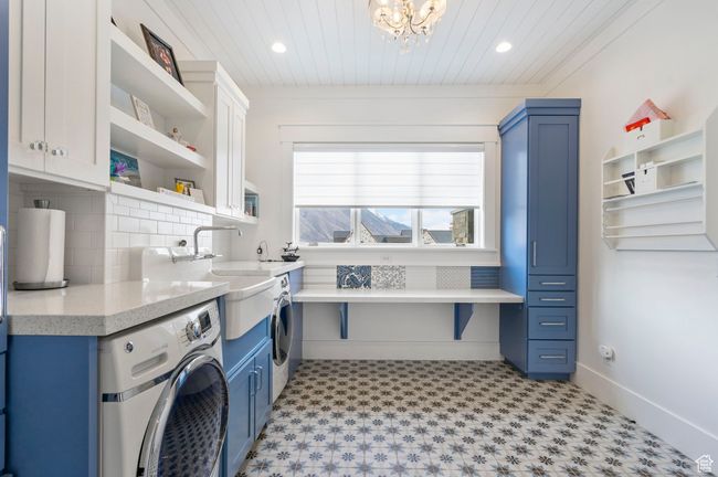 Clothes washing area with an inviting chandelier, cabinet space, light floors, washer and dryer, and wood ceiling | Image 18