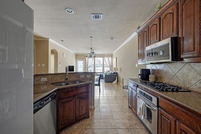 Kitchen with decorative backsplash, a sink, visible vents, stainless steel appliances, and a notable chandelier | Image 33
