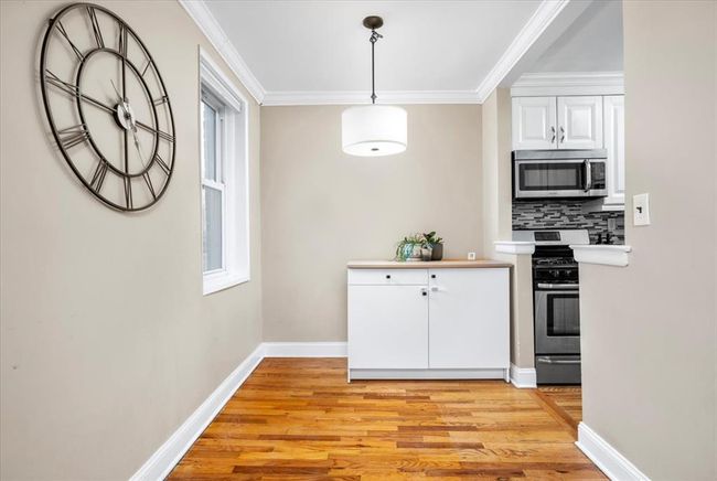 Kitchen with appliances with stainless steel finishes, light wood-type flooring, ornamental molding, white cabinetry, and light countertops | Image 10