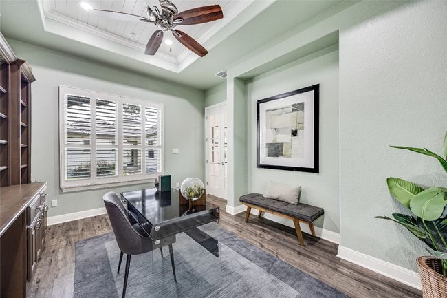 Office space with a tray ceiling, dark wood finished floors, ornamental molding, and a ceiling fan | Image 16
