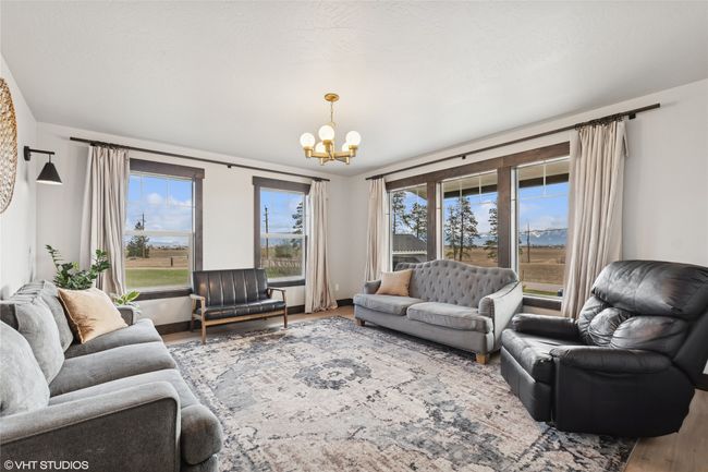 Living area featuring wood finished floors, an inviting chandelier, and a healthy amount of sunlight | Image 6