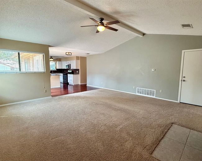 Unfurnished living room with ceiling fan, dark carpet, baseboards, and a textured ceiling | Image 5