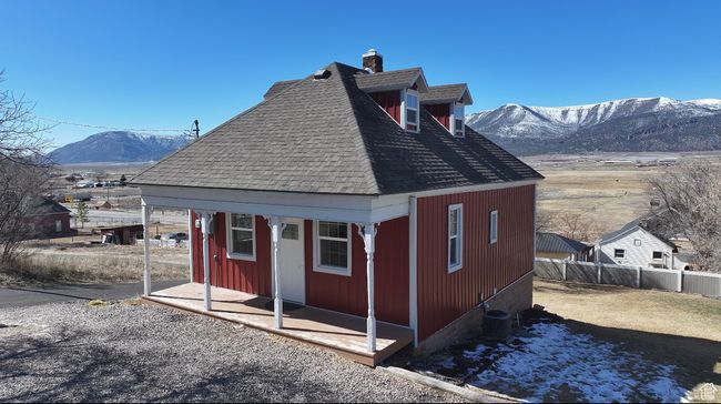View of home's exterior with a shingled roof, central AC unit, an outbuilding, fence, and a mountain view | Image 38