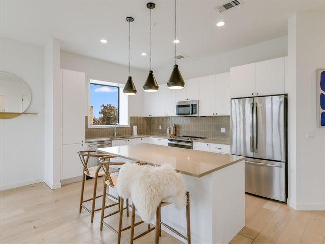 Kitchen with visible vents, backsplash, a kitchen island, appliances with stainless steel finishes, and light wood-style floors | Image 9
