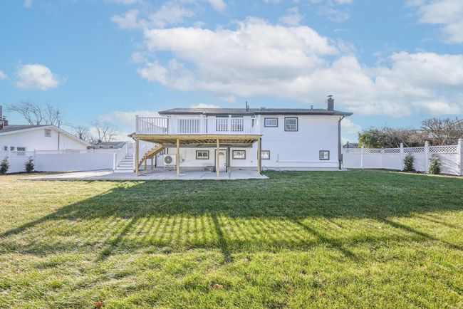Back of house with a wooden deck, a patio, and a lawn | Image 7