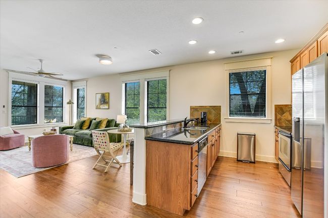 Kitchen with appliances with stainless steel finishes, a peninsula, a kitchen bar, light wood-type flooring, and recessed lighting | Image 10