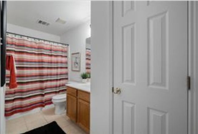 Bathroom with vanity, toilet, tile patterned floors, and a shower with shower curtain | Image 28