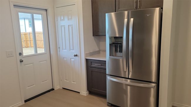 Kitchen with dark brown cabinets, stainless steel fridge with ice dispenser, and light countertops | Image 5