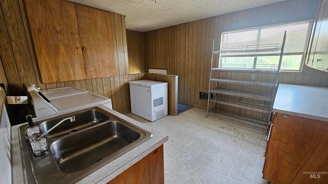 Laundry area featuring washing machine and dryer, wooden walls, light flooring, and cabinet space | Image 22
