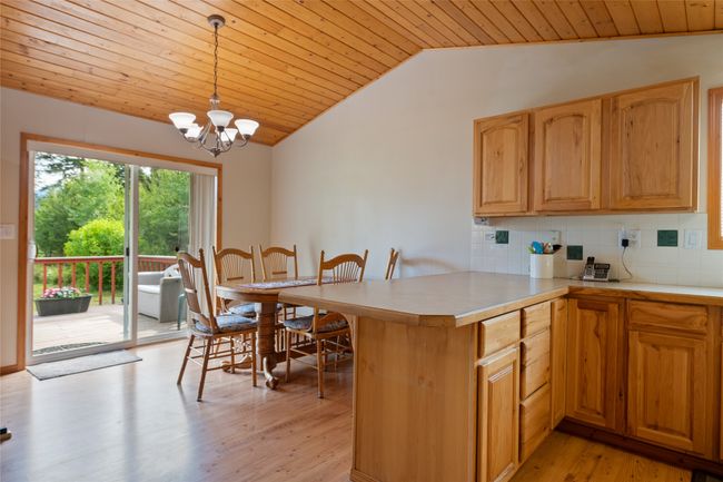Kitchen with lofted ceiling, wooden ceiling, light countertops, a peninsula, and backsplash | Image 24