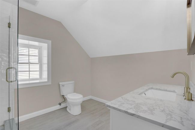 Bathroom featuring toilet, vaulted ceiling, a shower stall, wood finished floors, and baseboards | Image 21
