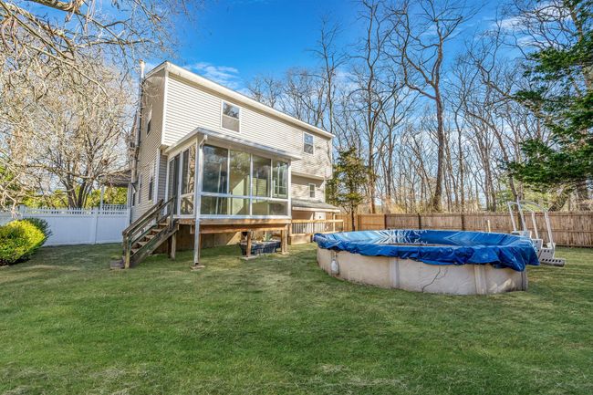 Back of house featuring a fenced backyard, a chimney, a sunroom, and a lawn | Image 26