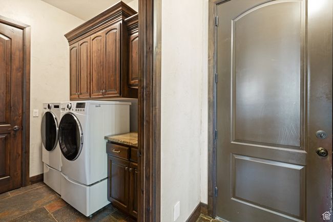 Laundry area with washing machine and clothes dryer, stone tile flooring, and cabinet space | Image 29
