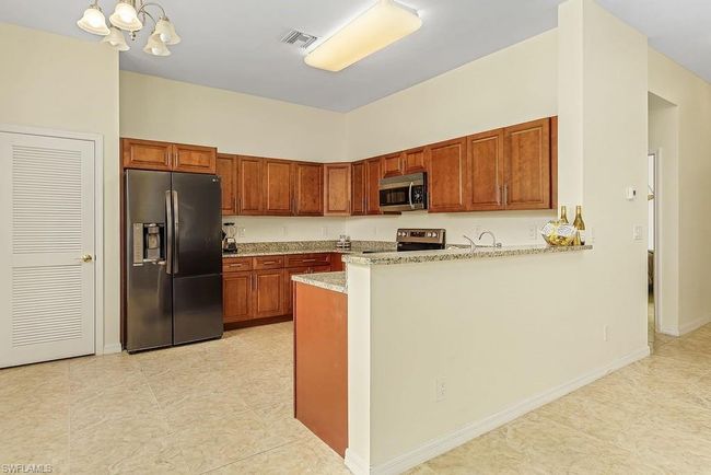 Kitchen with visible vents, a peninsula, brown cabinets, appliances with stainless steel finishes, and an inviting chandelier | Image 5