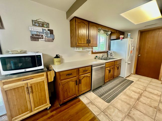 kitchen with dishwasher, a sink, freestanding refrigerator, and brown cabinets | Image 18