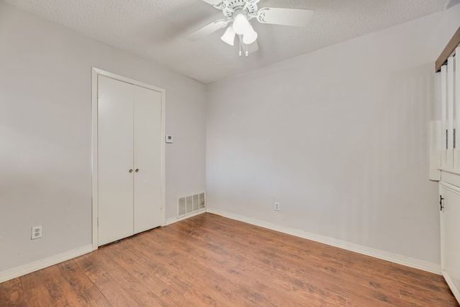 Unfurnished bedroom with wood finished floors, ceiling fan, and a textured ceiling | Image 6
