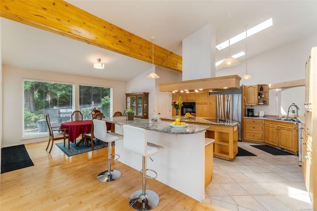 Kitchen with open shelves, a center island, stainless steel refrigerator, a sink, and a breakfast bar | Image 11