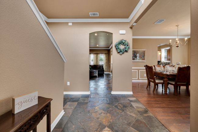 Entrance foyer featuring arched walkways, ornamental molding, stone tile floors, and a chandelier | Image 5
