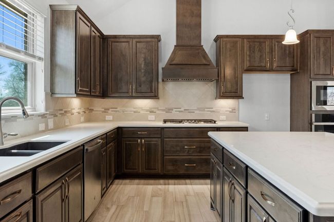 Kitchen with light countertops, custom range hood, appliances with stainless steel finishes, and a sink | Image 17