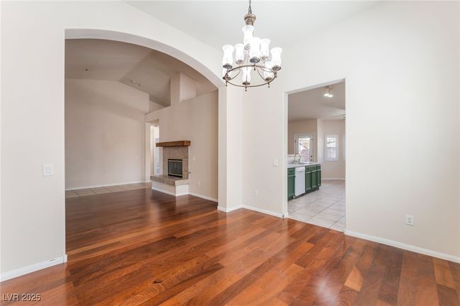 Unfurnished living room with light wood finished floors, a chandelier, vaulted ceiling, arched walkways, and a fireplace | Image 19