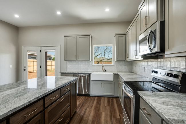 Kitchen featuring appliances with stainless steel finishes, gray cabinets, dark wood-style flooring, and a sink | Image 11
