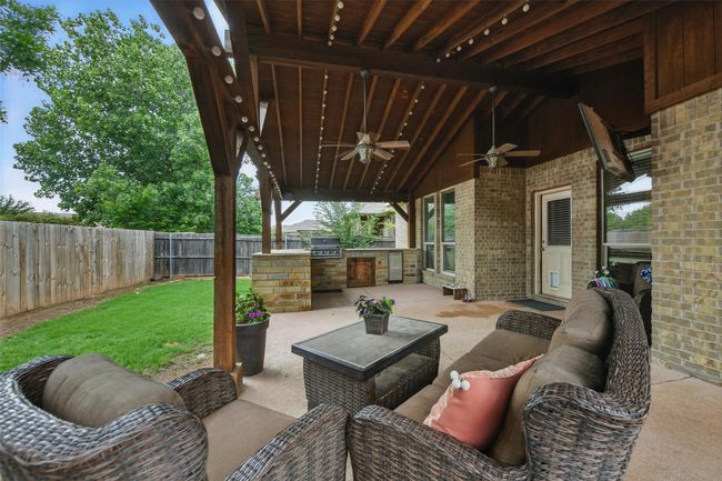 Fenced backyard featuring exterior kitchen, ceiling fan, a patio area, and an outdoor living space | Image 8