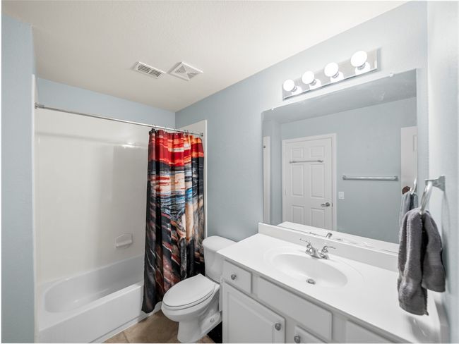 Bathroom with toilet, shower / bathtub combination with curtain, visible vents, and vanity | Image 25