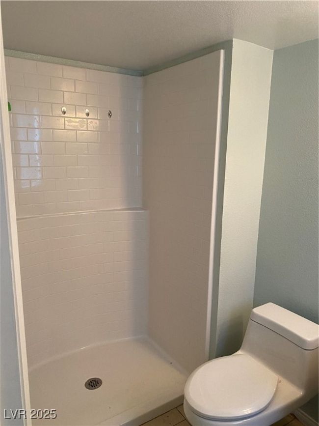 Bathroom featuring a shower stall, toilet, and a textured ceiling | Image 16
