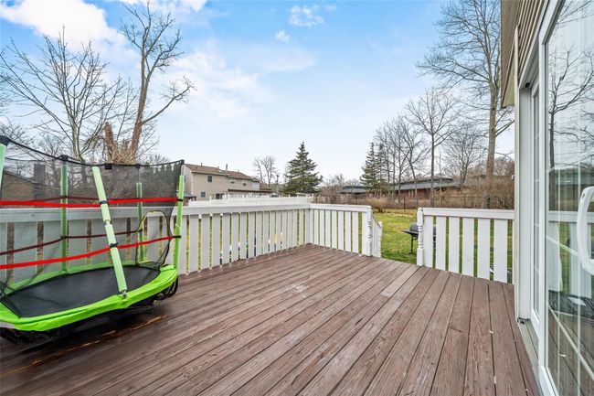 Wooden deck featuring a trampoline and a fenced backyard | Image 43