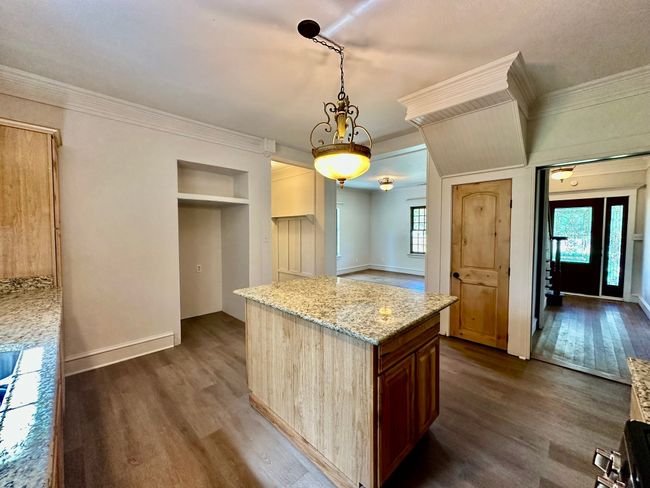 Kitchen featuring dark wood-style flooring, built in features, light stone counters, pendant lighting, and ornamental molding | Image 16