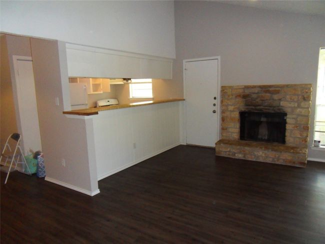 Unfurnished living room featuring dark wood finished floors, a fireplace, baseboards, and a towering ceiling | Image 4