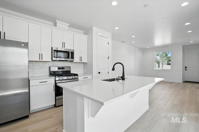 Kitchen with appliances with stainless steel finishes, an island with sink, light wood finished floors, recessed lighting, and decorative backsplash | Image 10