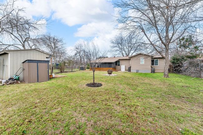 View of yard featuring a storage unit, an outdoor fire pit, fence, and an outdoor structure | Image 24