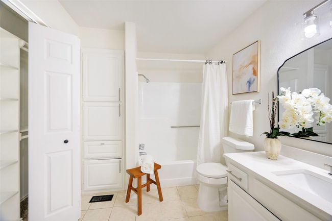 Full bath featuring tile patterned flooring, vanity, toilet, and shower / bath combo with shower curtain | Image 18