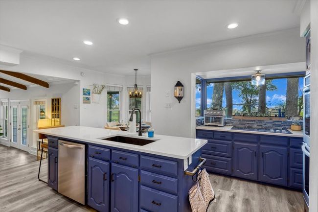 Kitchen featuring stainless steel dishwasher, blue cabinetry, black electric cooktop, a sink, and light wood-type flooring | Image 11