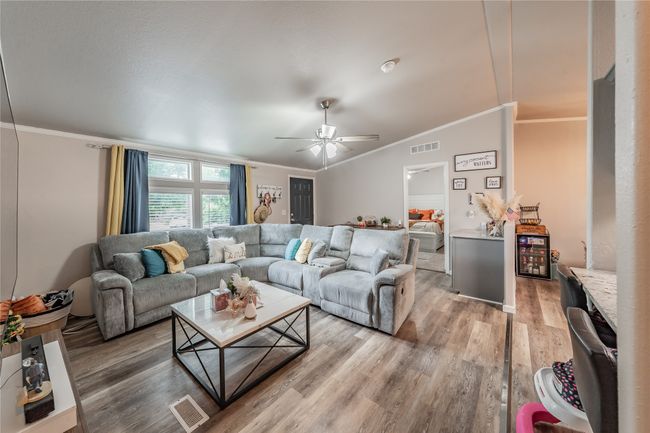 Living area with crown molding, light wood-style flooring, and a ceiling fan | Image 5