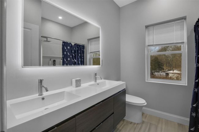 Bathroom with a shower with shower curtain, vanity, and toilet | Image 21