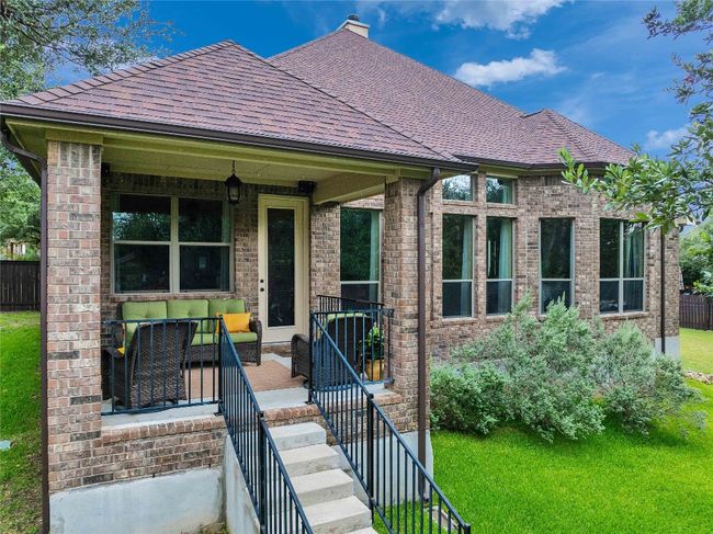 View of back of house with brick siding, a shingled roof, outdoor lounge area. | Image 5