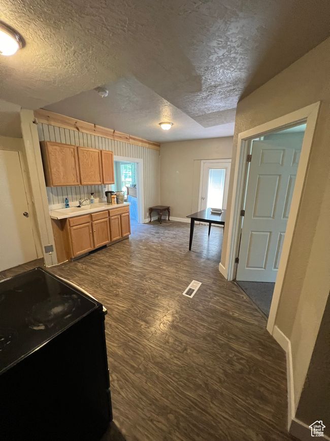 Kitchen featuring dark wood-style floors, black / electric stove, visible vents, baseboards, and a textured ceiling | Image 6