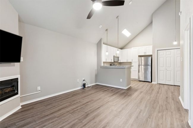 Unfurnished living room featuring ceiling fan, light wood-type flooring, and high vaulted ceiling | Image 6